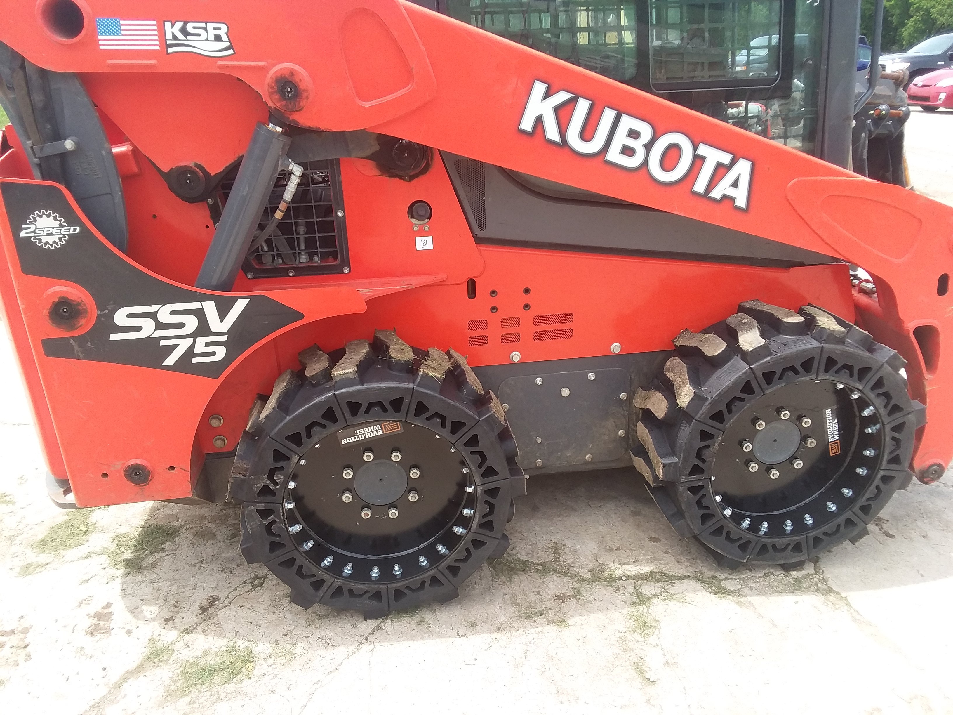 This images shows a red Kubota skid steer using our all terrain solid skid steer tires.