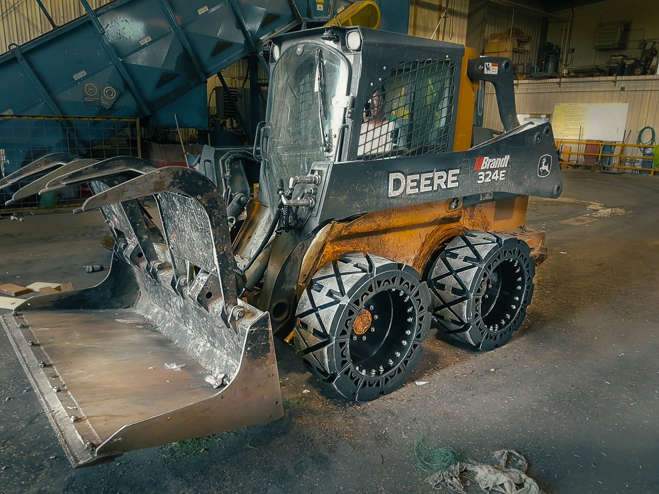 This image shows a DEERE 324E with our Airless Skid Steer Tires the EWRS-HS