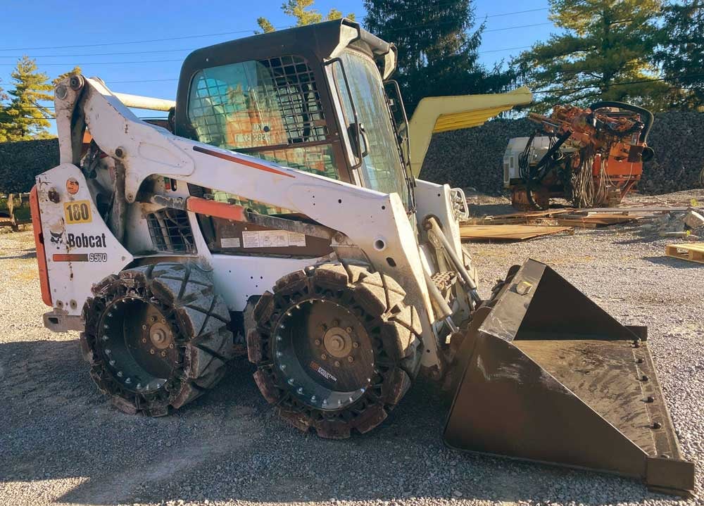 This image has a Bobcat S570 skid steer using our bobcat hard surface skid steer tires.