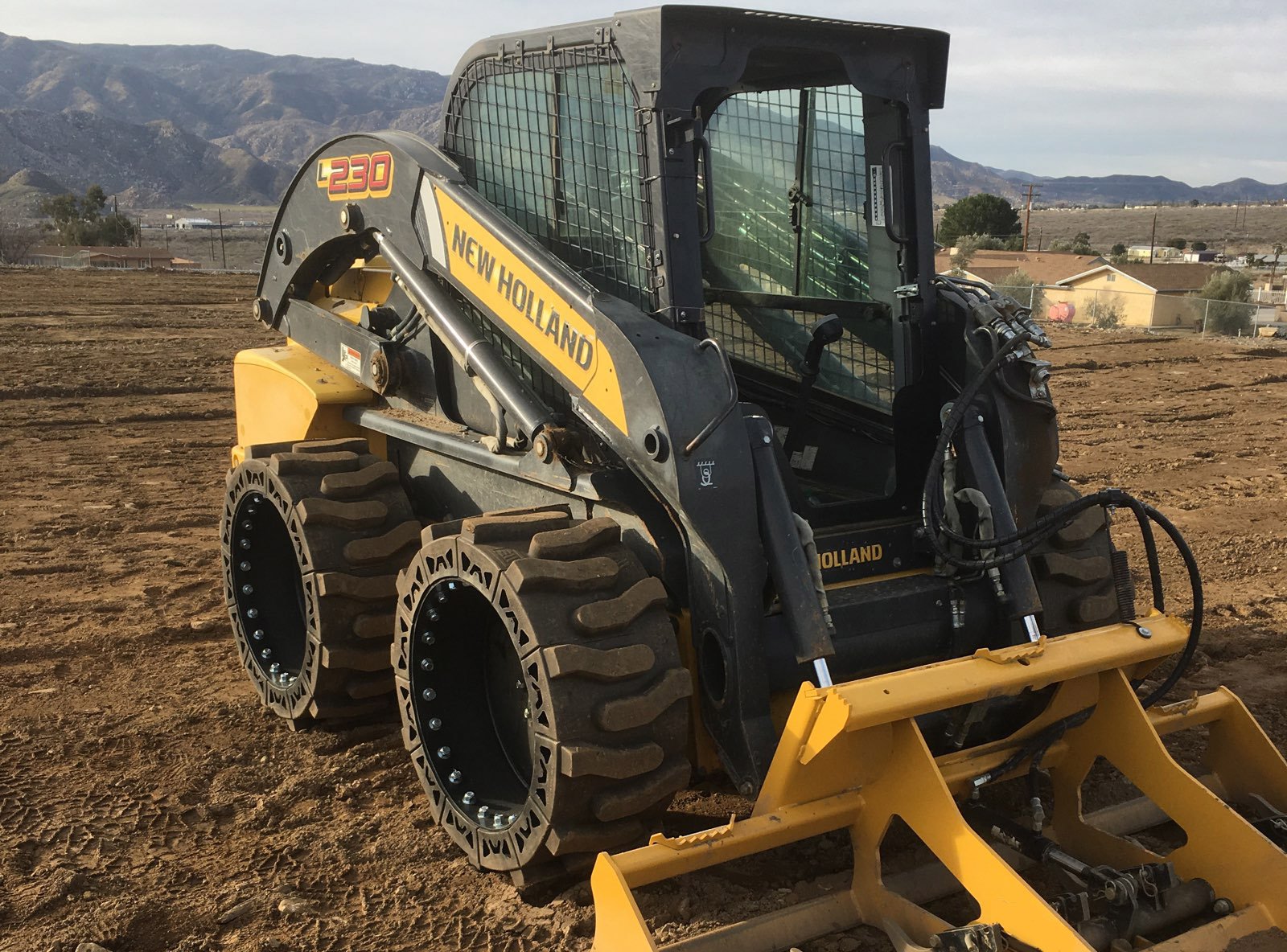 This image is about a yellow New Holland skid steer using our Bobcat all terrain skid steer tires