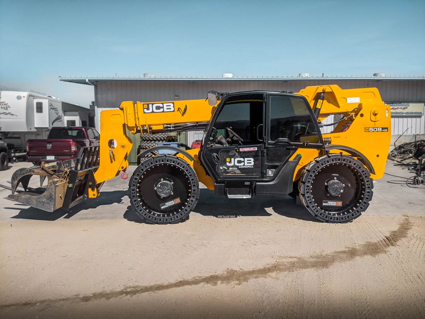 This picture shows solid telehandler tires on a black and yellow JCB telehandler