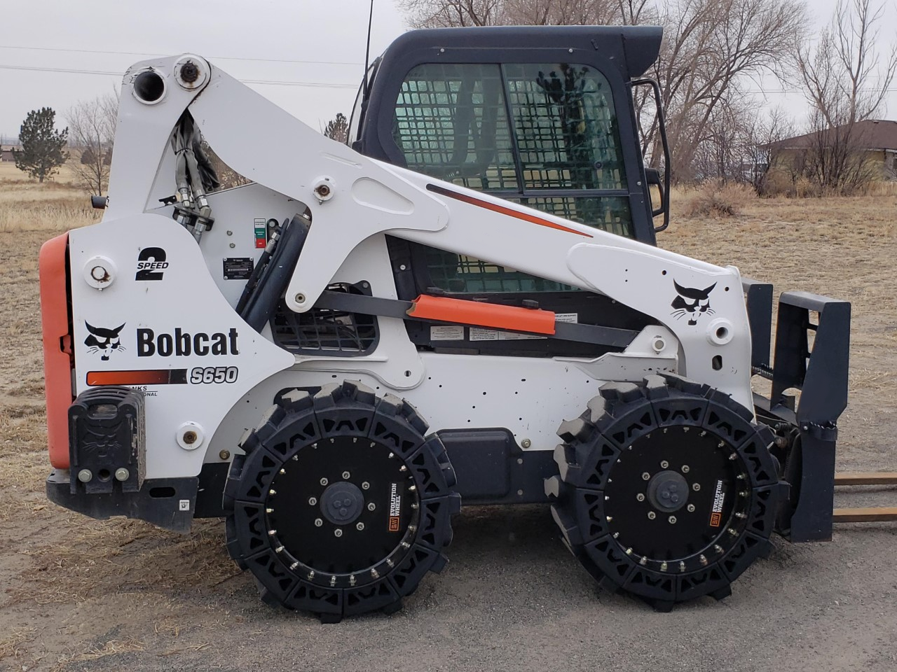This image shows a White Bobcat S650 Skid Steer using our all terrain skid steer tires.