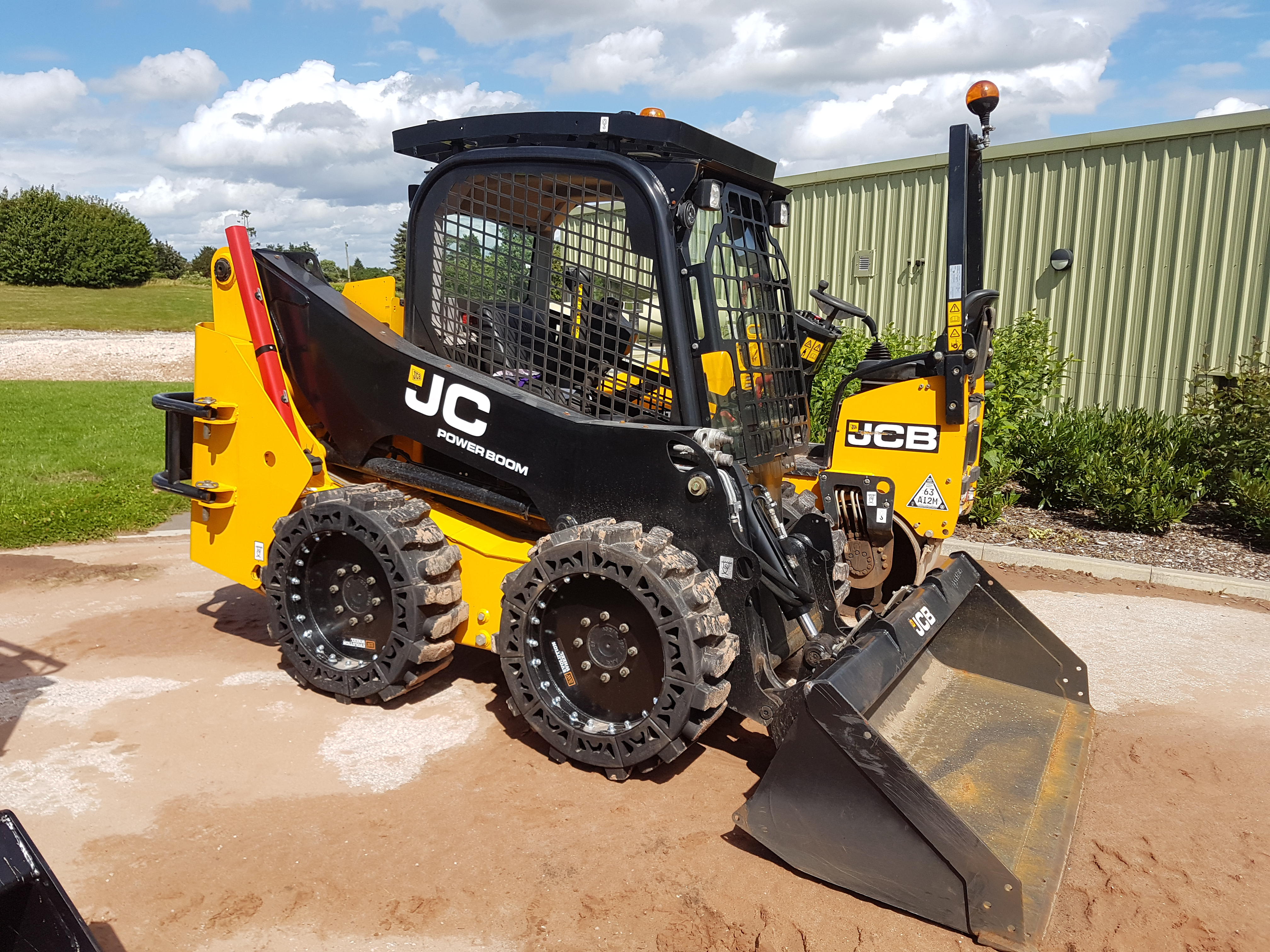 This images shows a yellow JCB Skid Steer using our14x17.5 Solid Skid Steer Tires