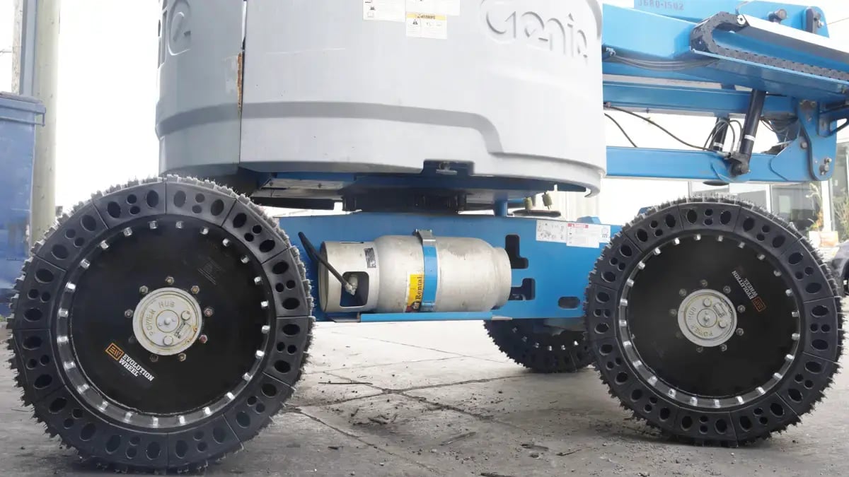 Evolution Wheel EWRS-AWP solid tires mounted on a Genie AWP machine parked in a demanding industrial rental yard.