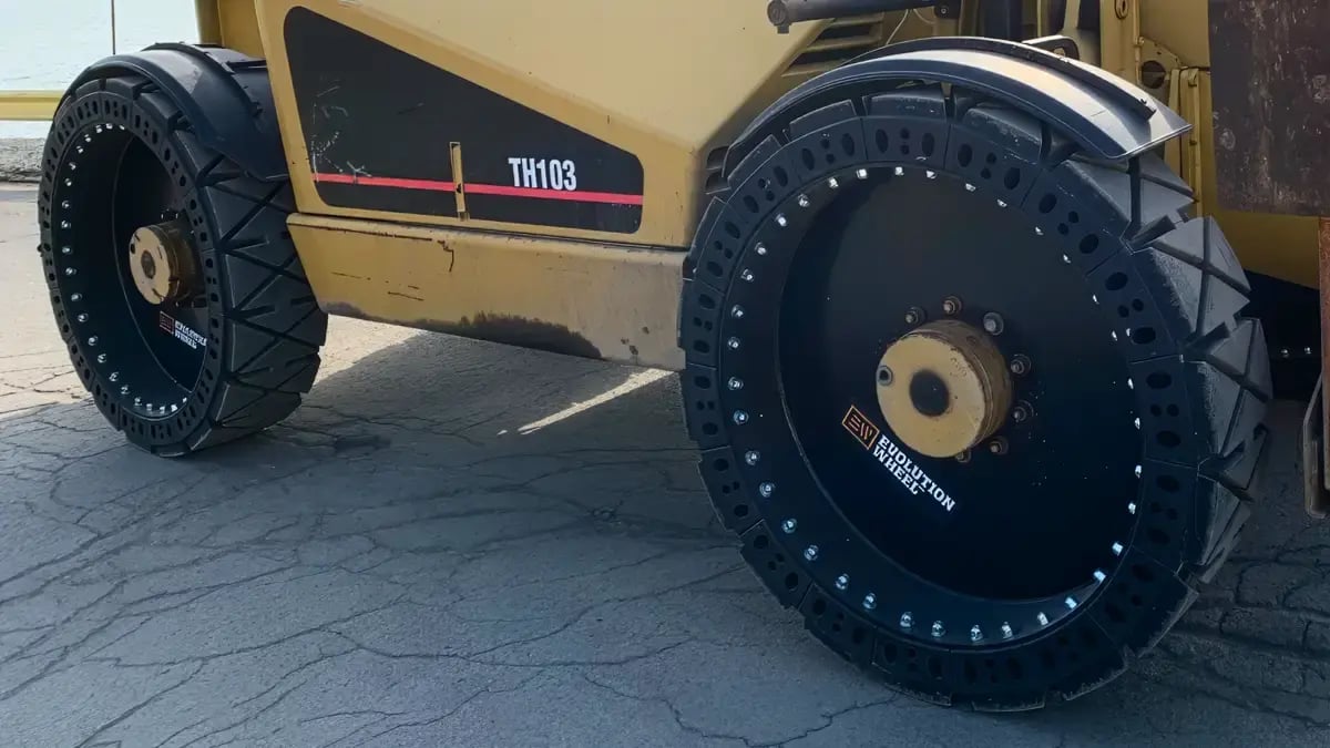 A Caterpillar telehandler operating with durable airless tires on a solid surface
