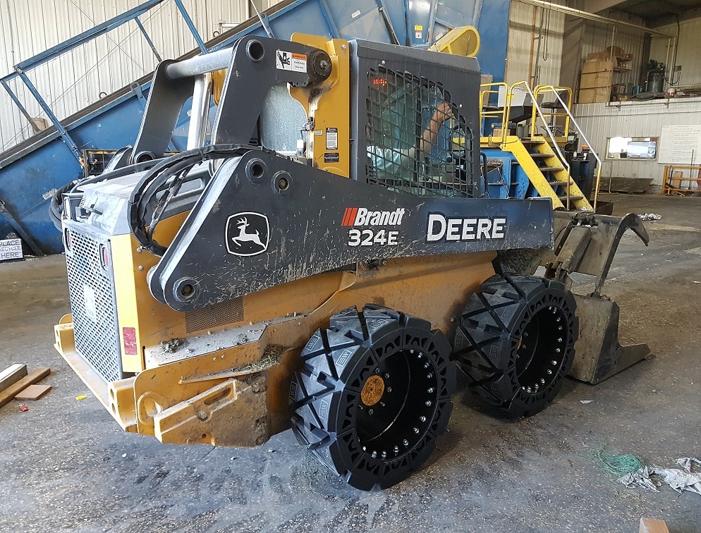 This images shows a skid steer using our EWRS-HS solid skid steer tires in a junk yard.