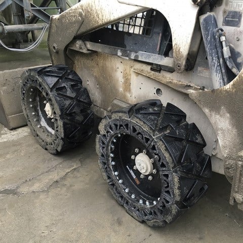 This image shows a skid steer with our EWRS-HS solid skid steer tires on a jobsite, being used on a hard surface application.