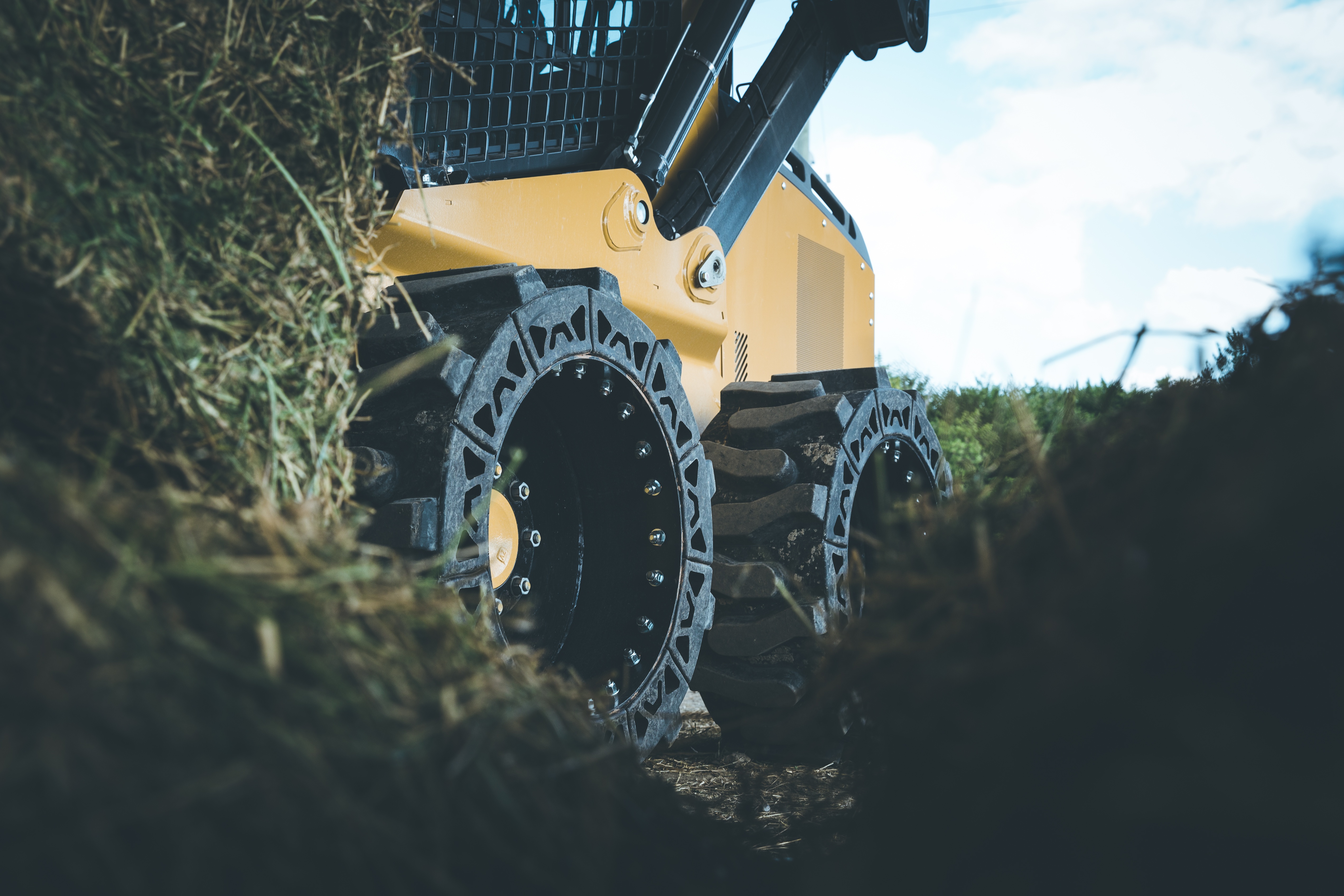 This images shows a skid steer using our EWRS-AT solid skid steer tires on a jobsite field. 