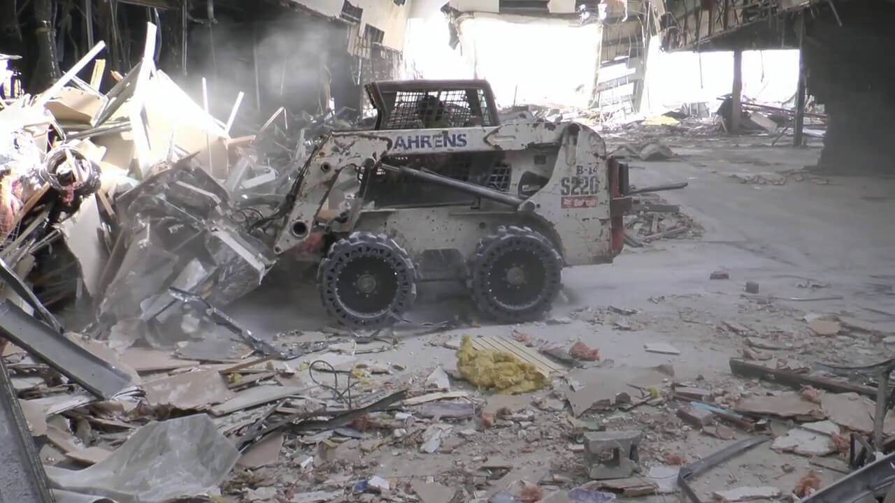 This images shows a skid steer using our EWRS-AT solid skid steer tires on a  jobsite