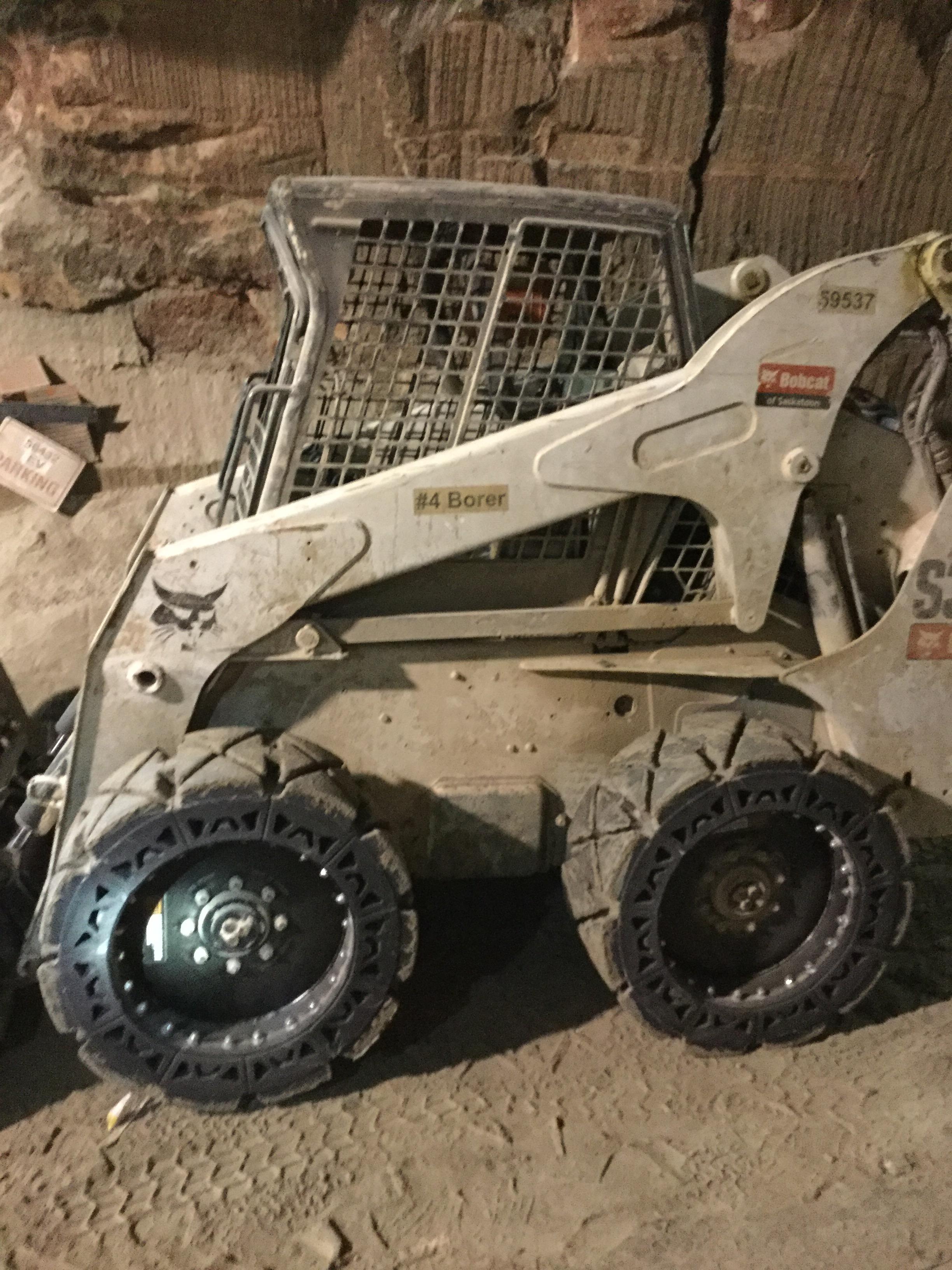 This image shows a white Bobcat skid steer with our EWRS-HS tires on a jobsite.