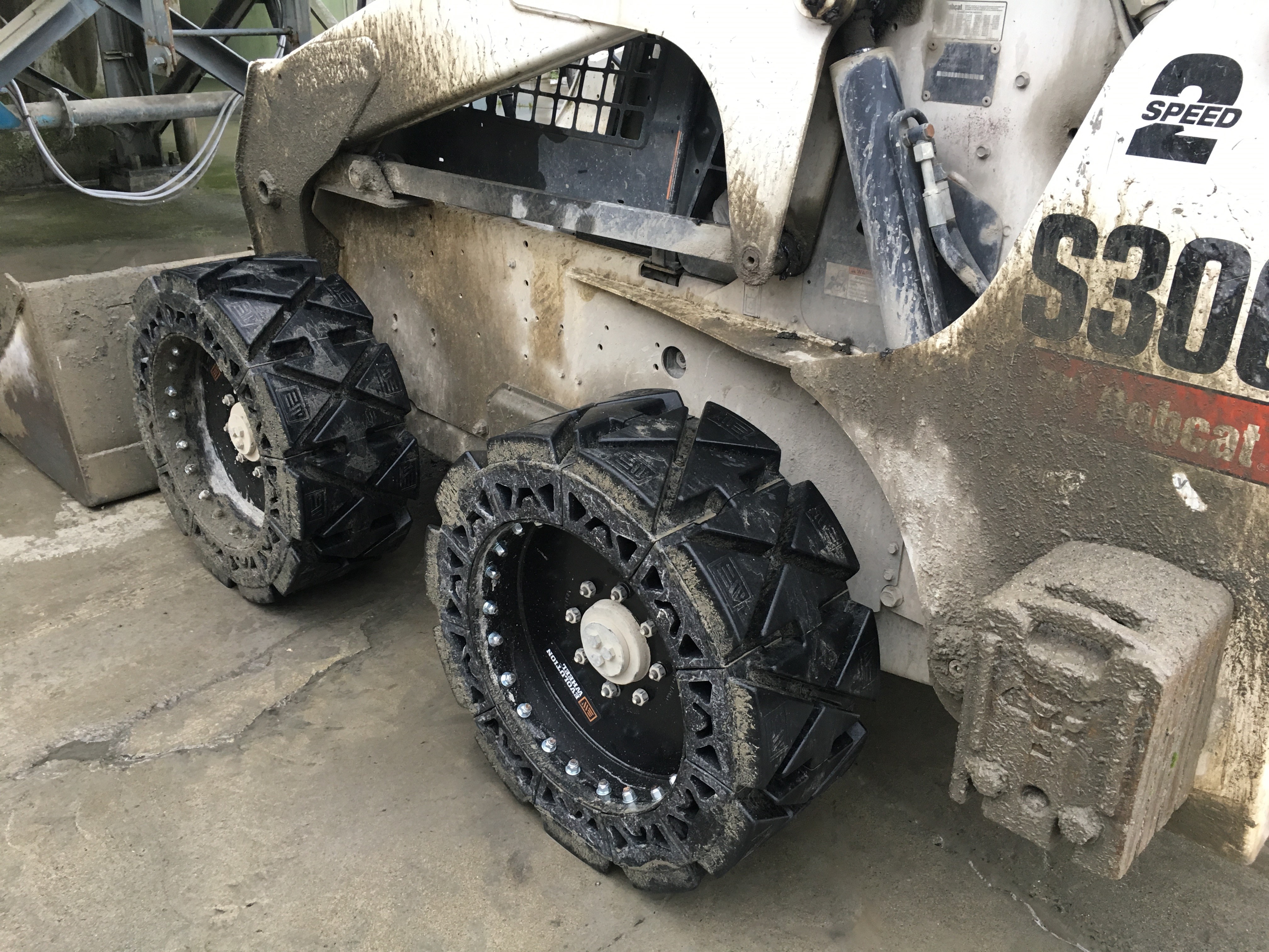 This images shows a white bobcat skid steer in a jobsite using our EWRS-HS solid skid steer tires. 