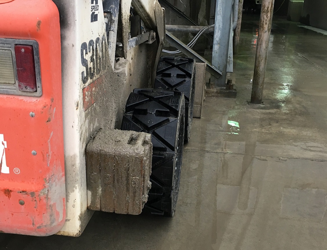 This image shows a Bobcat skid steer using our EWRS-HS solid skid steer tires on a hard surface like concrete.
